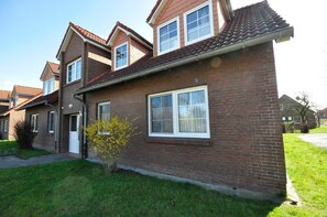 A two-story brick house with a red-tiled roof, a small front yard, and a single-story neighbor.