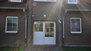 Een tweelaags bakstenen gebouw met een centrale ingang, twee ramen aan elke kant, en het cijfer '1A' zichtbaar aan de rechterkant.