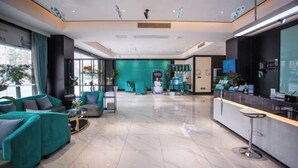 Un moderno vestíbulo de hotel con sofás color turquesa, un mostrador de recepción y una pared verde.