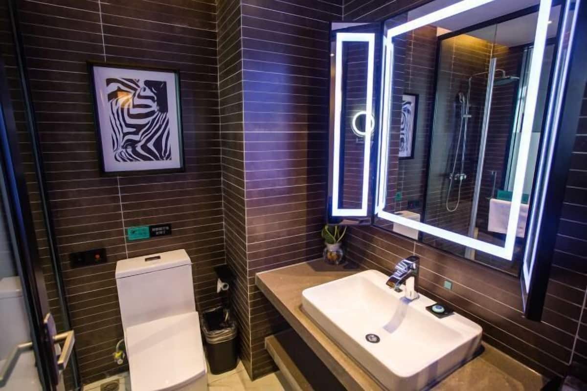 Un baño moderno con un espejo grande, un inodoro y un lavamanos.