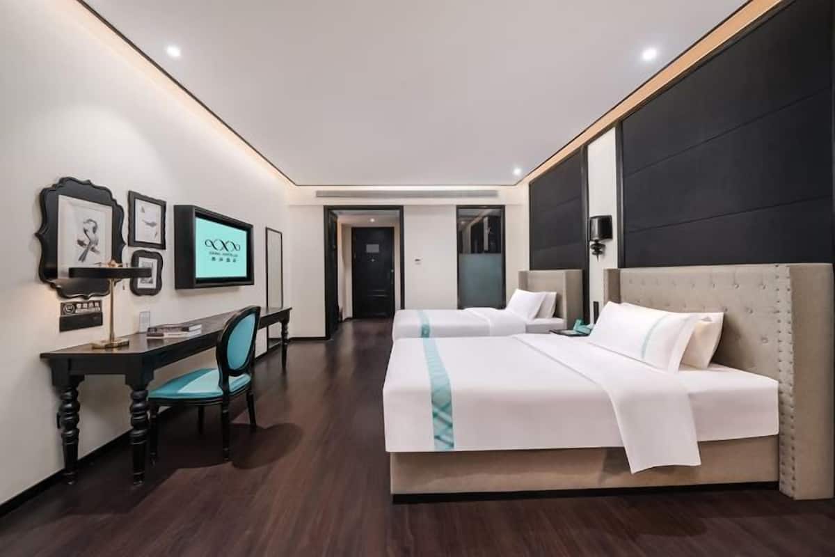 Una habitación de hotel con cama, escritorio, silla y televisión.