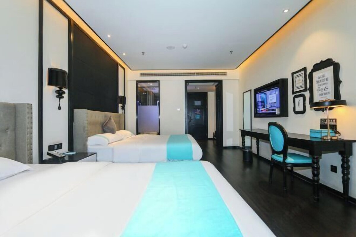 A modern hotel room with a large bed, a desk, and a television.