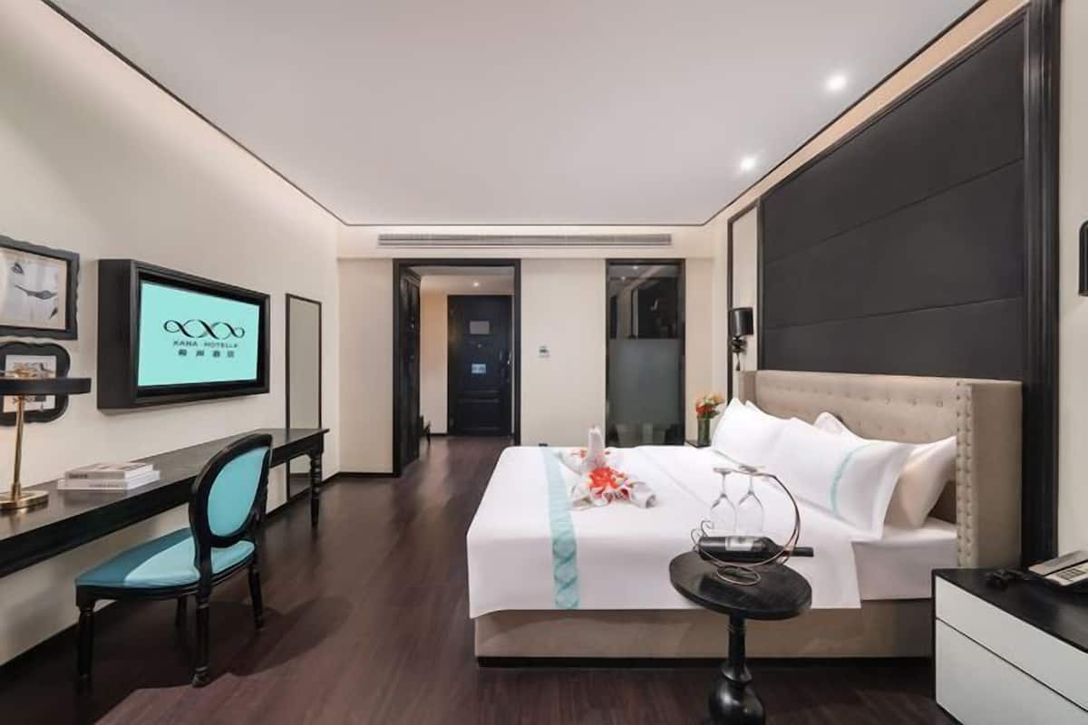 Una habitación de hotel con cama, escritorio, silla, televisor y mesita de noche.