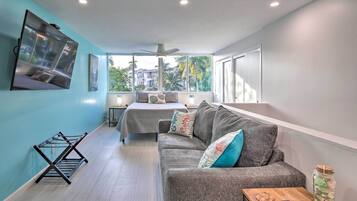 A modern living room with a grey sofa, a coffee table, and a TV mounted on the wall.