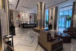 A hotel lobby with a reception desk, seating area, and large windows. - Pinju Wanguo Hotel (Dushan)