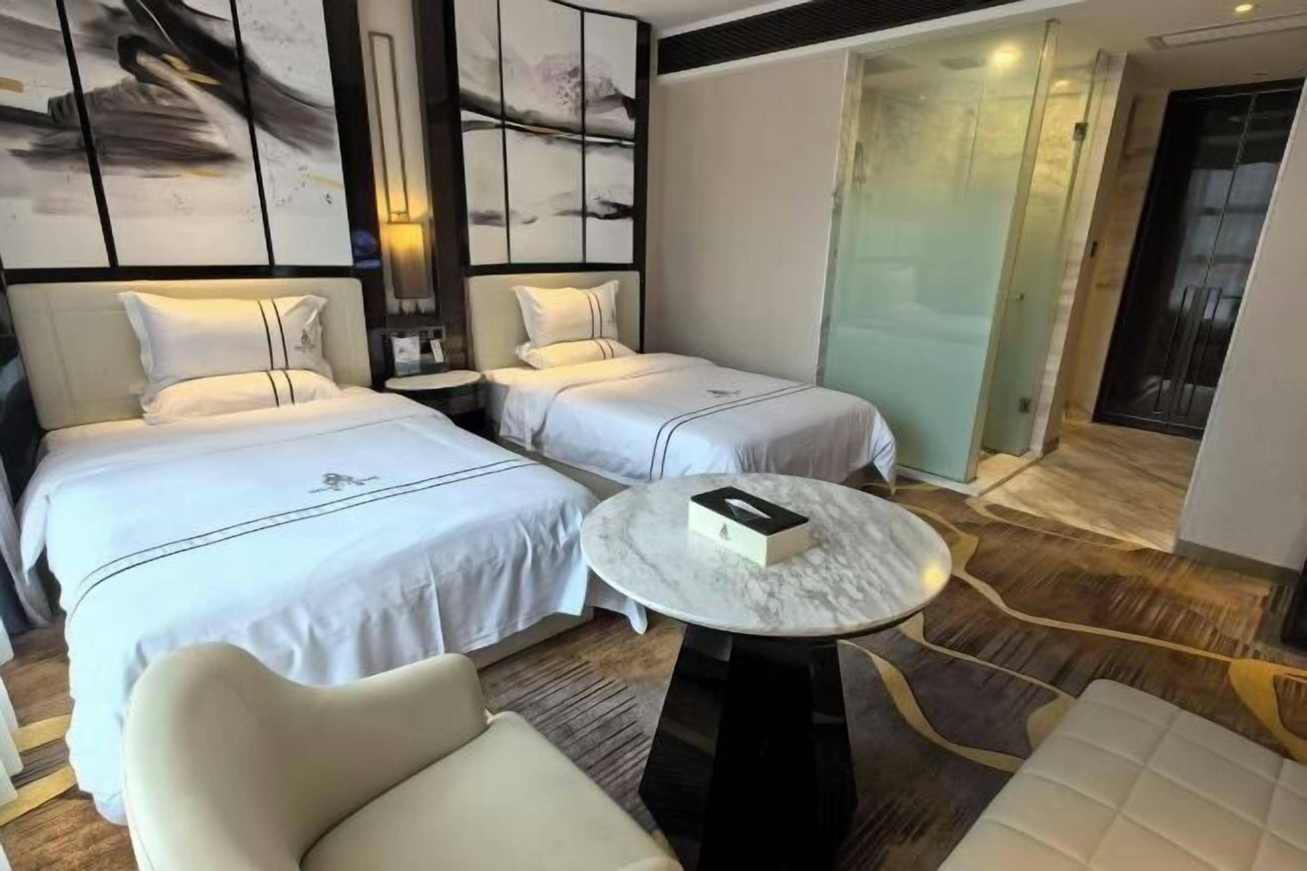 Une chambre d’hôtel avec deux lits, une table ronde en marbre et un design moderne.