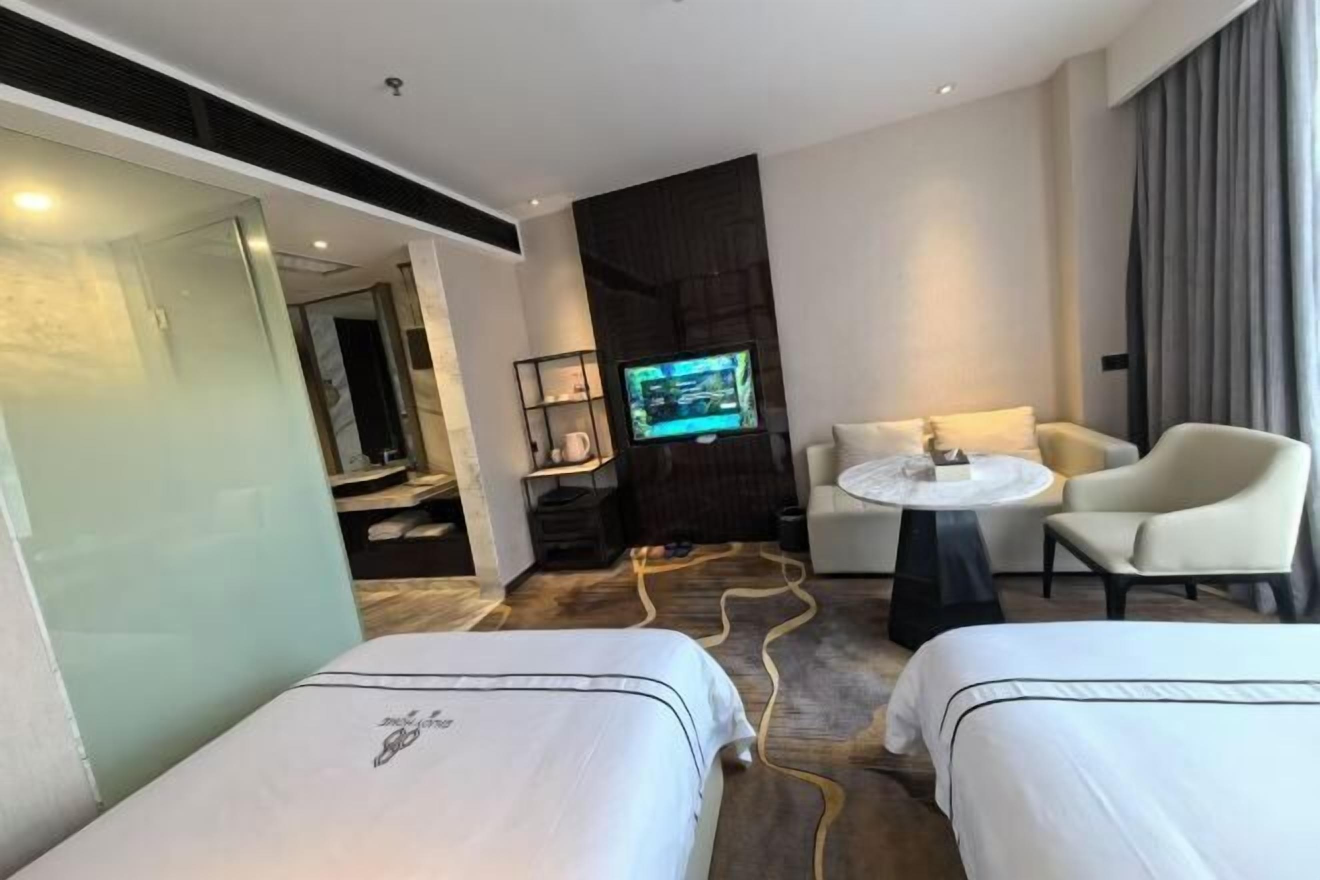 A hotel room with two beds, a TV, a small table, and a sofa.