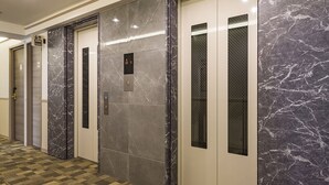 Un ascensor moderno con paredes de mármol y suelo cubierto de alfombra a cuadros.
