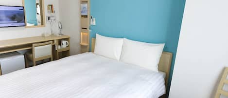 A hotel room with a bed, a desk, a chair, a TV, and a mirror.