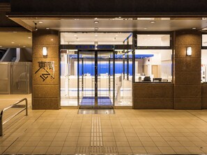 Entrada de hotel con puerta giratoria, recepción y un letrero con caracteres japoneses.