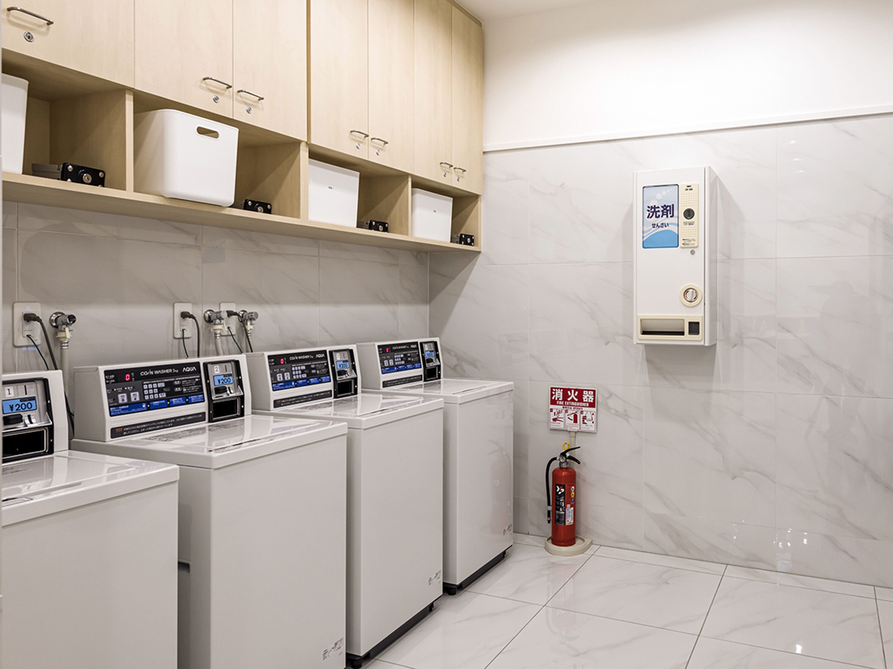 A laundry room with multiple washing machines, a fire extinguisher, and a water heater.