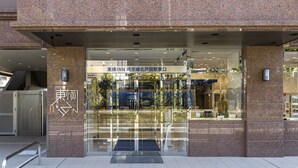La entrada de un edificio con fachada de vidrio, un letrero que indica un lugar y una rampa para accesibilidad.