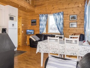A cozy cabin interior with a dining table, a sofa, a television, and a kitchen area with appliances. - Saana 1 by Interhome (Enontekiö)