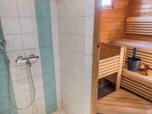A sauna with a wooden bench and a metal bucket.