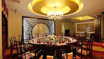 A dining area with a round table, chairs, and a chandelier.