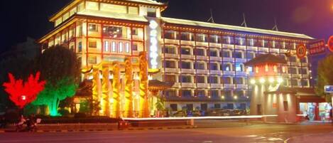Un hotel de varios pisos con un diseño arquitectónico tradicional, que destaca por una entrada imponente y un letrero iluminado de gran tamaño.