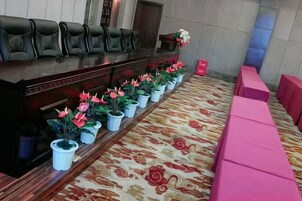 Zona de recepción con un mostrador alargado, varias sillas y una fila de plantas en macetas.