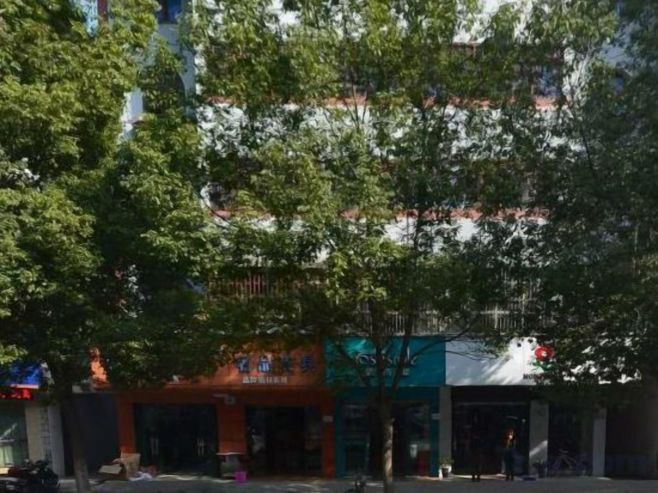 A street view with buildings, trees, and a clear sky.