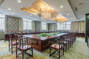 A conference room with a large rectangular table surrounded by chairs, a chandelier, and large windows. - Laoying International Hotel (Danjiangkou)