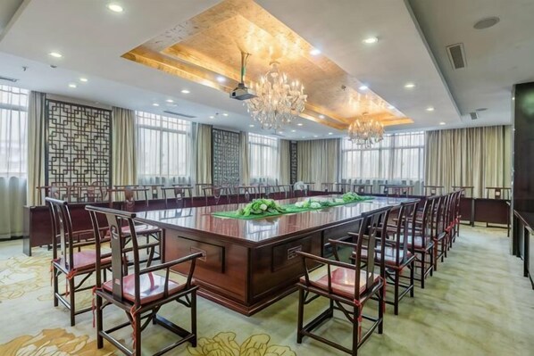 A conference room with a large rectangular table surrounded by chairs, a chandelier, and large windows. - Laoying International Hotel (Danjiangkou)