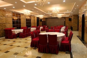 A banquet hall with round tables, red chairs, and chandeliers. - Laoying International Hotel (Danjiangkou)