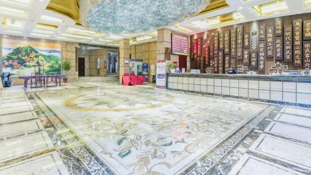 A hotel lobby with a large chandelier, a reception desk, and a decorative wall with calligraphy. - Laoying International Hotel (Danjiangkou)
