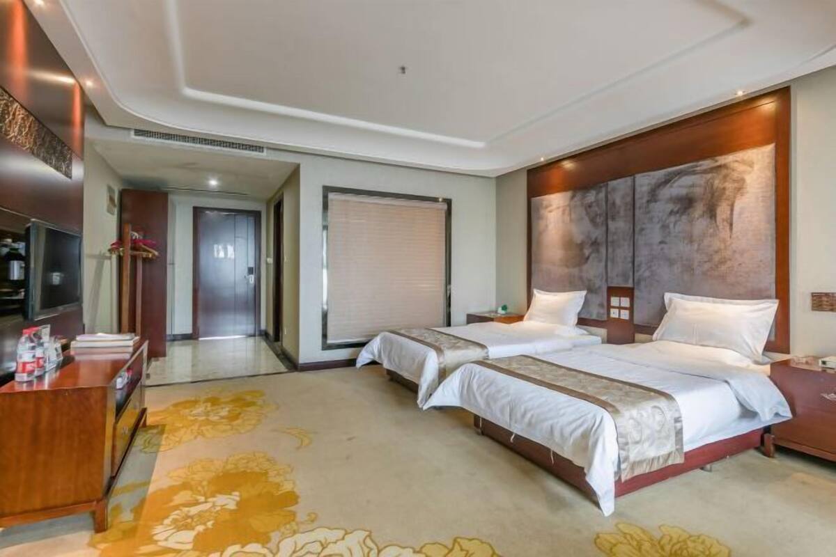 A hotel room with two beds, a desk, and a large artwork on the wall.
