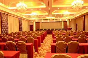 A conference room with rows of chairs, a carpeted floor, and chandeliers. - Laoying International Hotel (Danjiangkou)