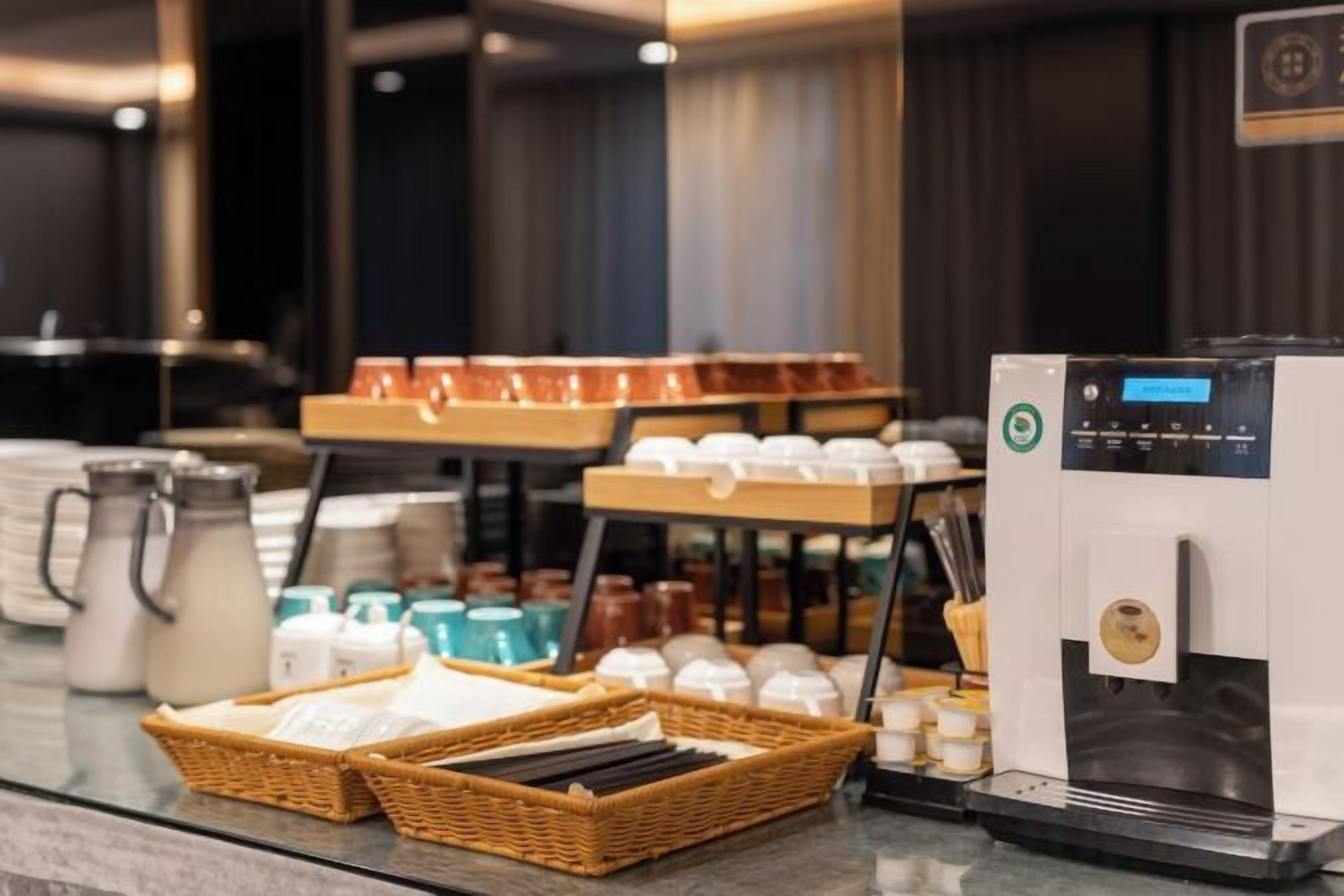 Una estación de café con una máquina de café, tazas y varios recipientes para café.