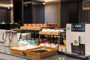 A coffee station with a coffee machine, cups, and various coffee containers.