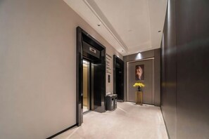A hallway with a door, a trash bin, and a wall-mounted sign. - Radow Hotel Chain (Wenzhou Railway Station) (Wenzhou)