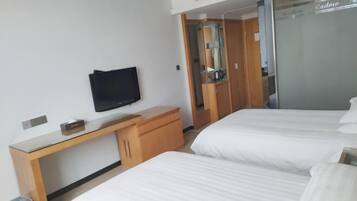 Une chambre d’hôtel avec deux lits, une télévision, un bureau et une armoire.