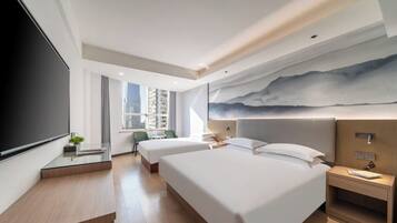 A modern hotel room with two beds, a large TV, a desk with a chair, and a city view.