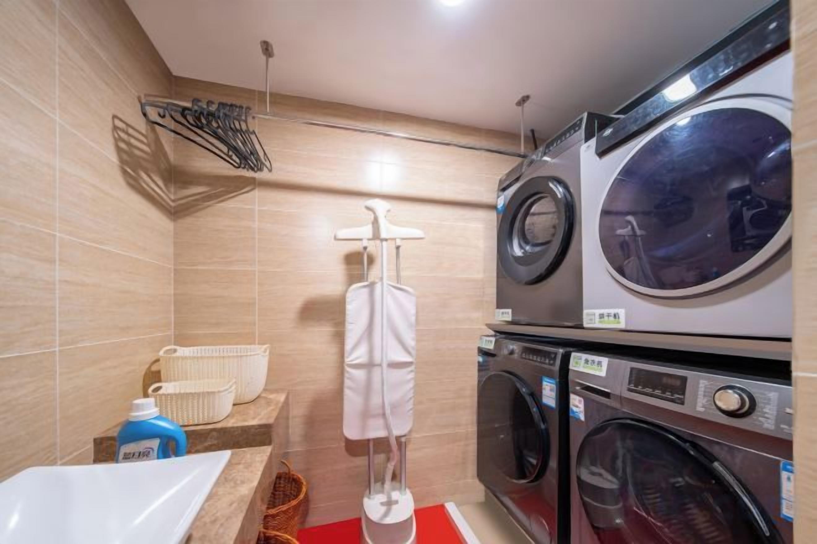 Un lavadero con lavadoras apiladas, un tendedero y un lavabo.