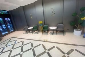 A lobby with a geometric patterned floor, a reception desk, green and gray chairs, and a potted plant. - Radow Hotel Chain (Wenzhou Railway Station) (Wenzhou)