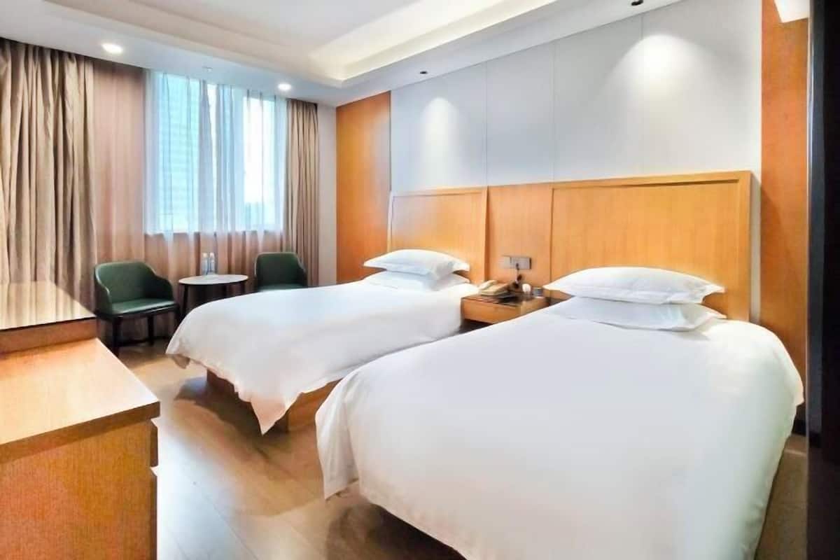 A hotel room with two beds, a desk, a chair, and a small table.