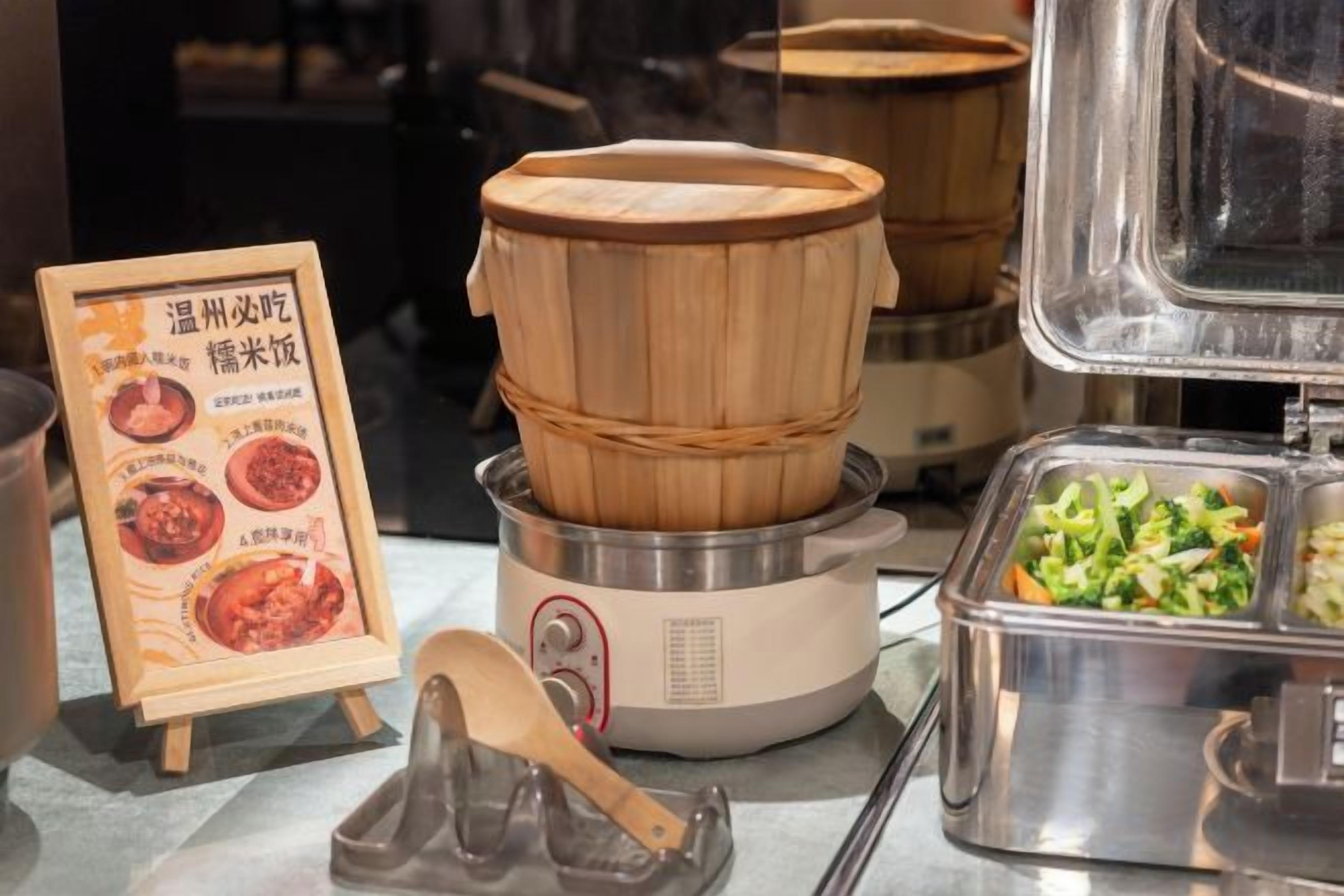 A buffet setup with a wooden steamer and a menu stand.
