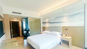 Une chambre d’hôtel moderne avec un grand lit, une table de chevet avec une lampe et un téléphone fixé au mur.