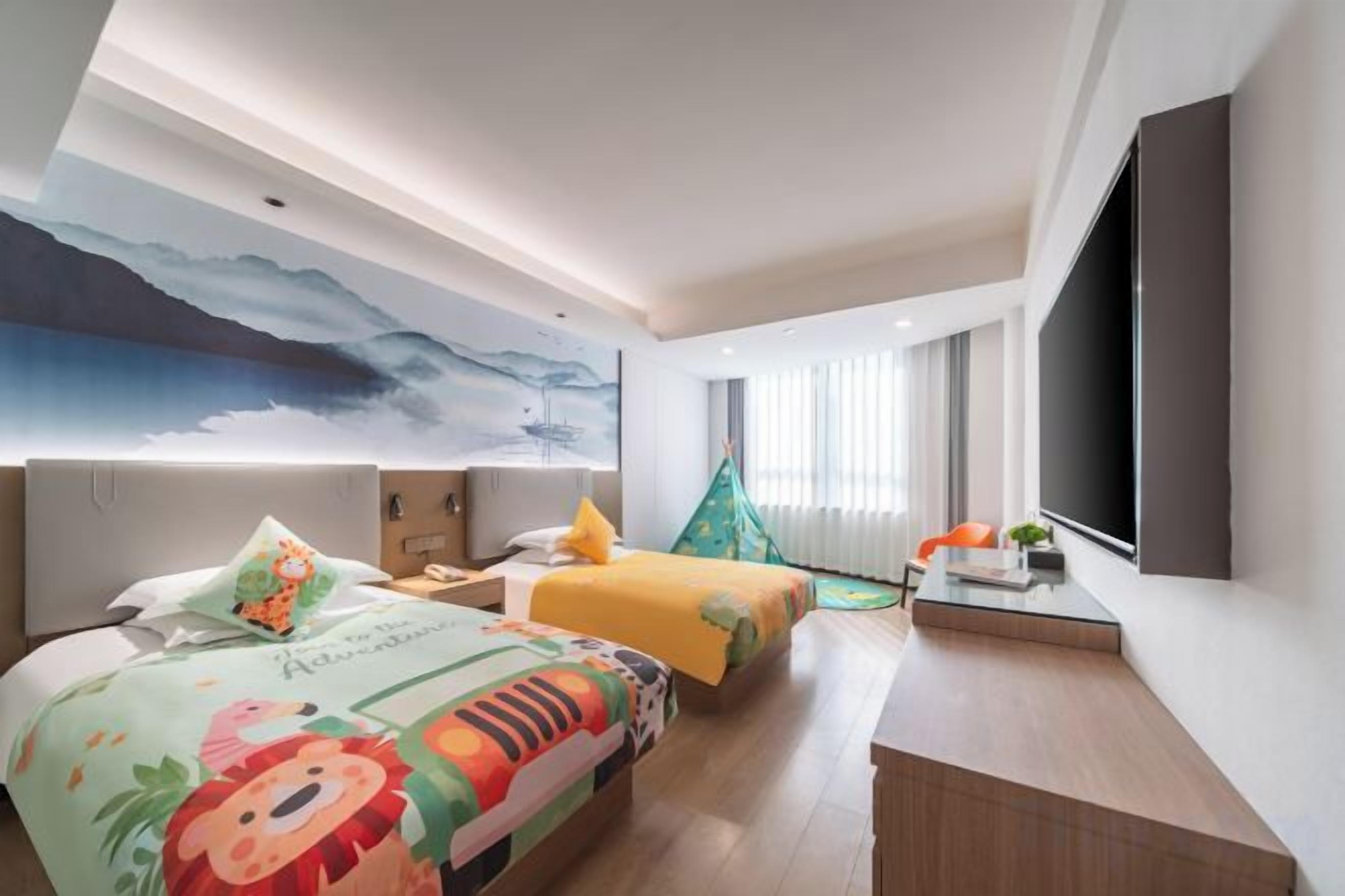 A hotel room with a large bed, a desk, a chair, a TV, and a window with curtains.