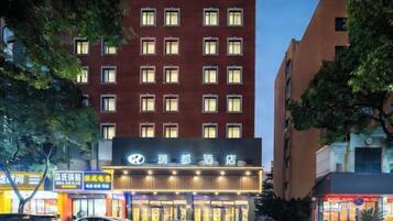A hotel with multiple floors, a prominent sign, and several cars parked in front.