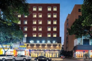 A hotel with multiple floors, a prominent sign, and several cars parked in front.