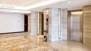 Una moderna hall d'albergo con pavimento in marmo, tappeto decorato e reception.
