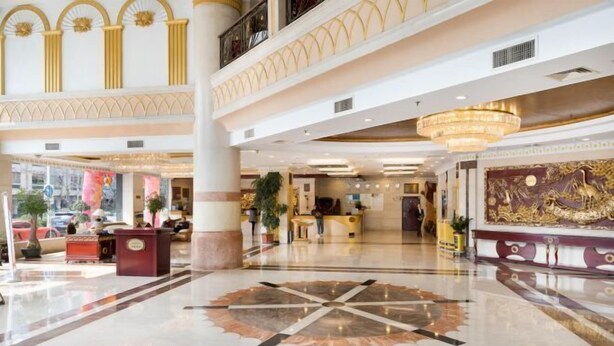 Un'ampia hall con un lampadario centrale, una reception e una parete decorativa.