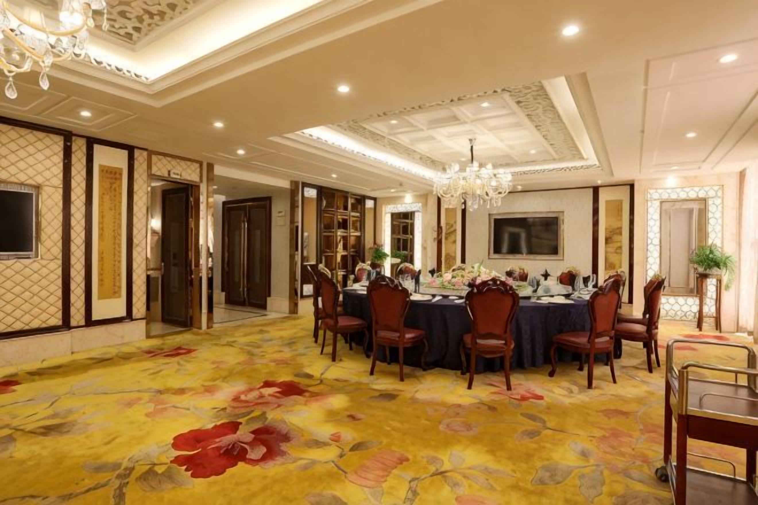 A formal dining room with a large round table, chairs, and a chandelier.