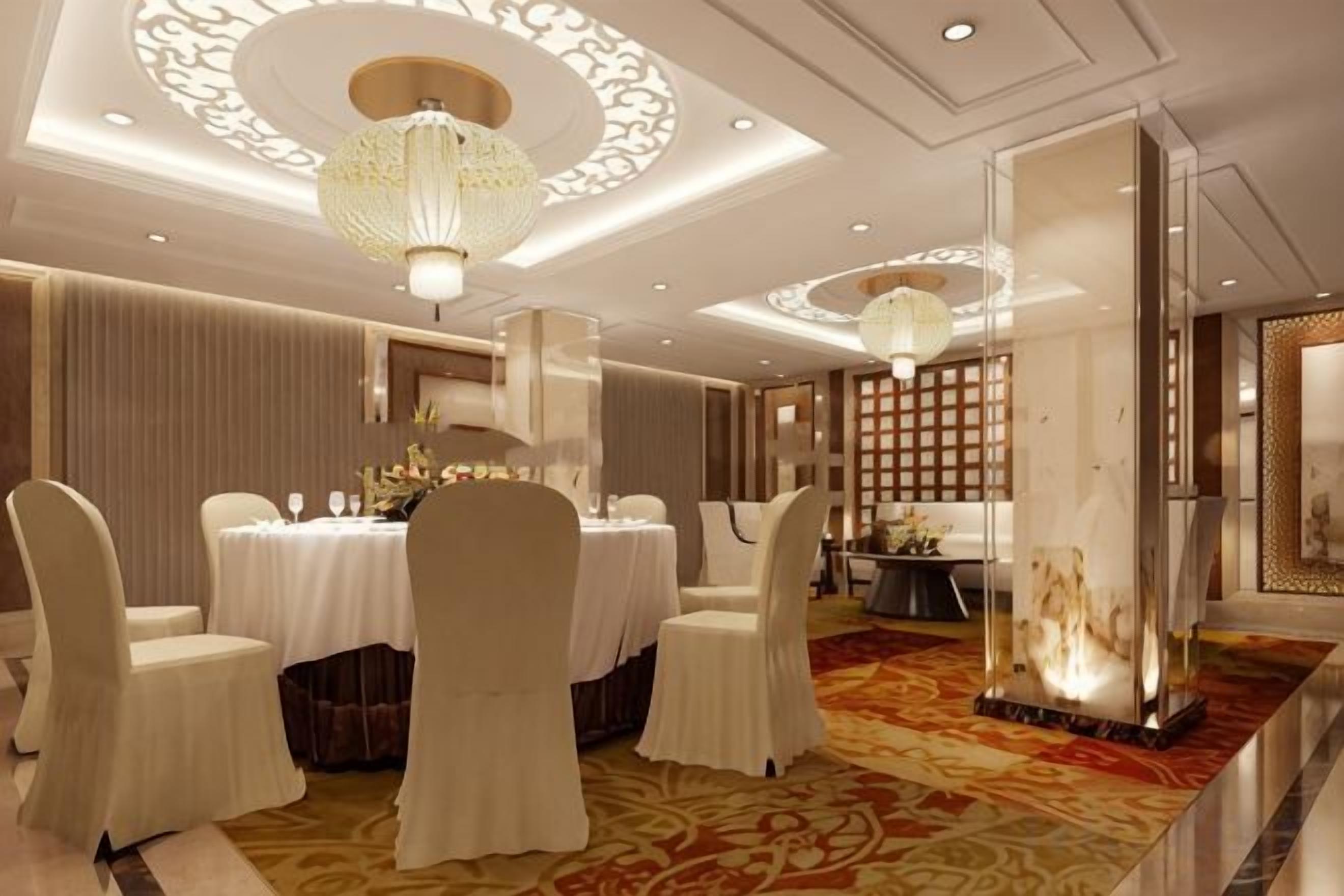 A formal dining room with a round table, white chairs, and a chandelier.