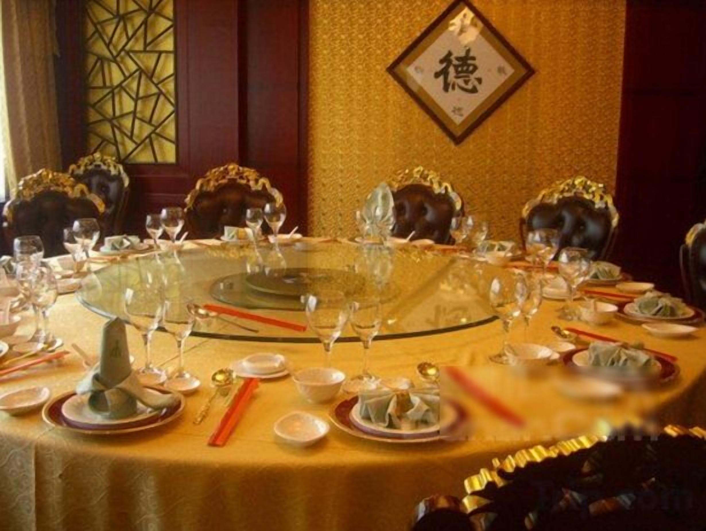 A round table set for a meal with chairs, plates, and cutlery.