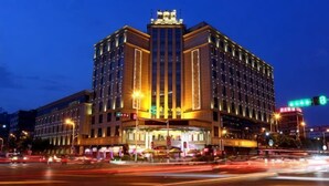 Un hotel a più piani con un ingresso centrale ben visibile, una vasta facciata in vetro e un design architettonico moderno.