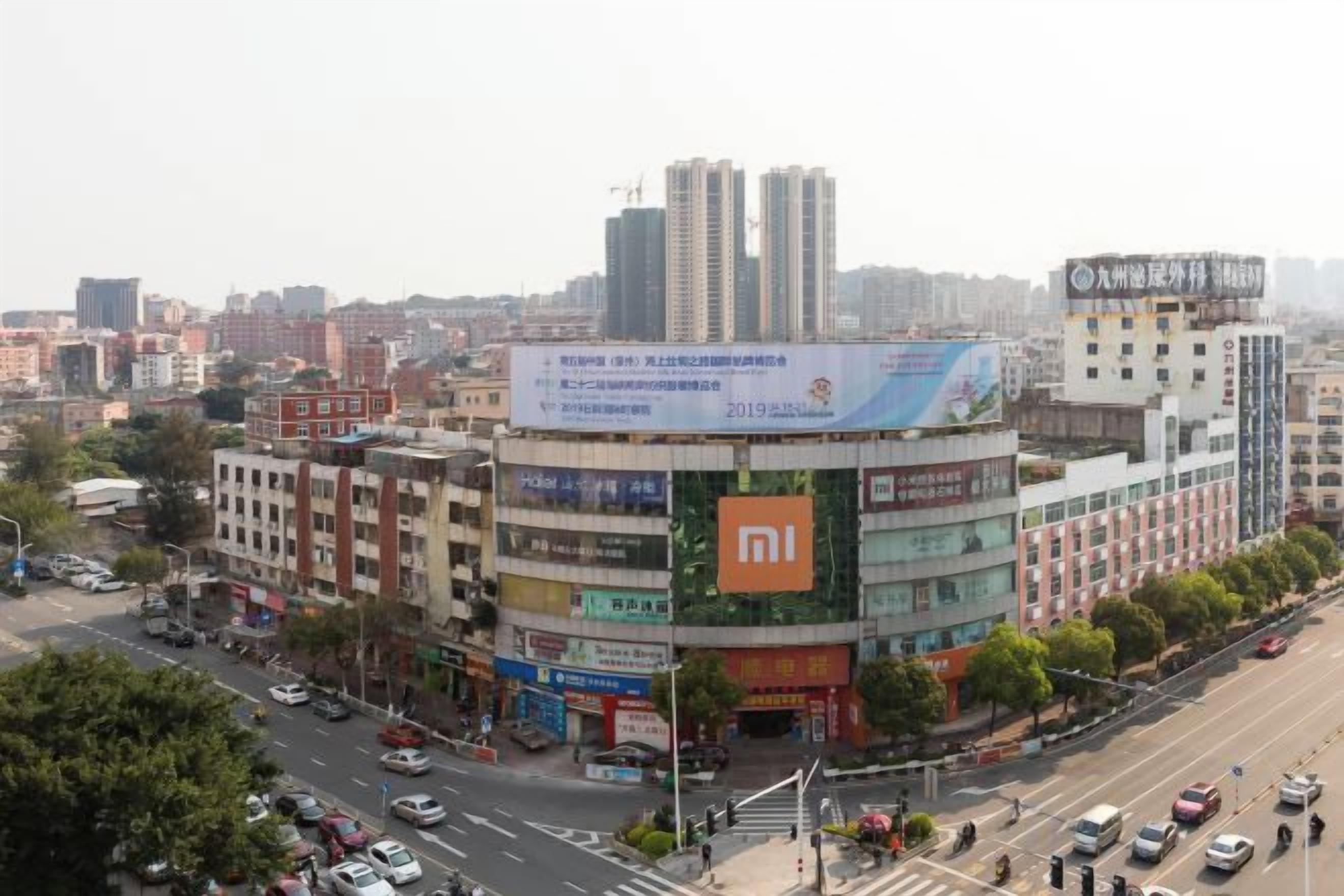 A multi-story building with a prominent Xiaomi advertisement on the facade, surrounded by other commercial buildings and a busy street.