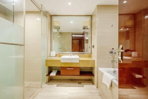 Un baño moderno con cabina de ducha de vidrio, tocador de madera con lavamanos y un espejo grande.