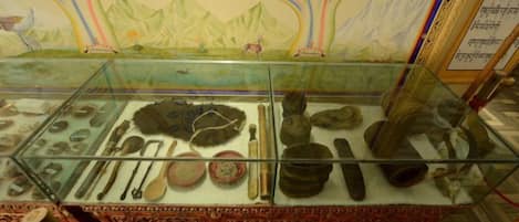 Una vitrina de museo exhibe diversos artefactos, como cerámica y herramientas, frente a un mural colorido.